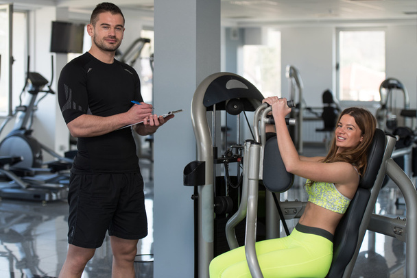 Woman Train Chest On Machine With Personal Trainer - Photo, image