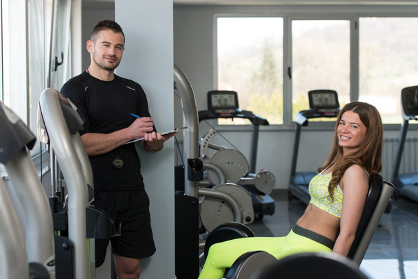 Personal Trainer Takes Notes While Woman Exercising Legs - Foto, Bild