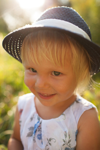 Cute little blonde smiling girl in a blue hat - Fotografie, Obrázek