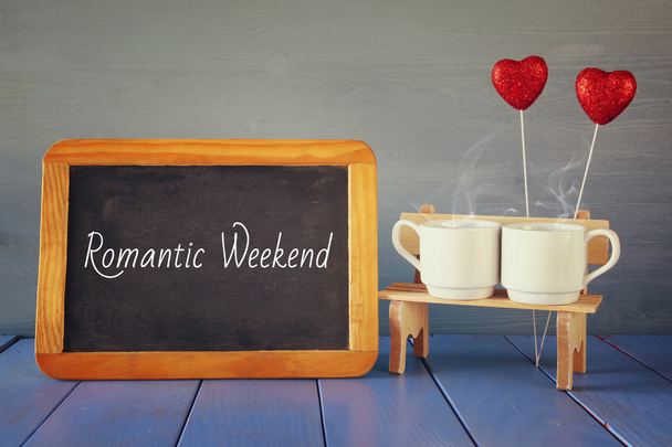 coffee cups next to blackboard with text: ROMANTIC WEEKEND - Photo, image