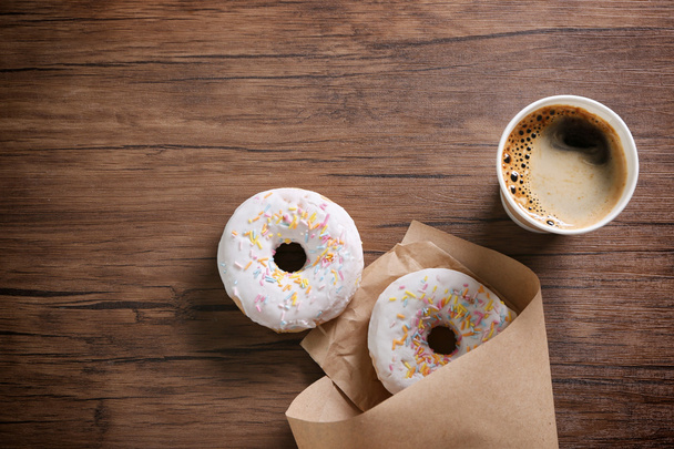 Paper cup of coffee and doughnuts on wooden background - Foto, Bild