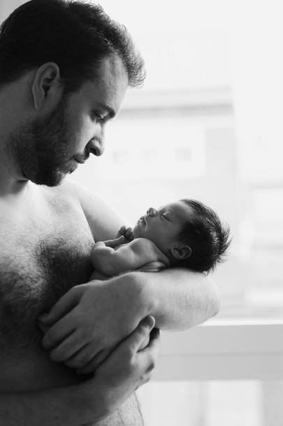 Отец голый смотрит на своего новорожденного ребенка
 - Фото, изображение