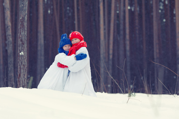Happy brother and sister in costumes snowman walking in winter forest, - Foto, imagen