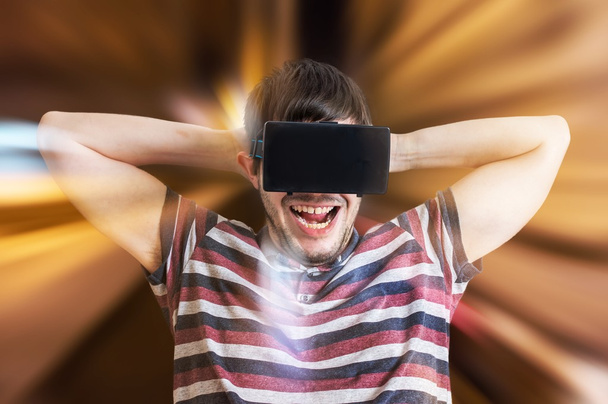 Young happy and excited man is wearing 3D virtual reality glasses and is playing  - Photo, Image