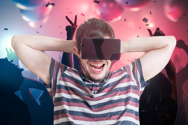 Молодой счастливый человек взволнован 3D очками виртуальной реальности. У него вечеринка в ночном клубе.
. - Фото, изображение
