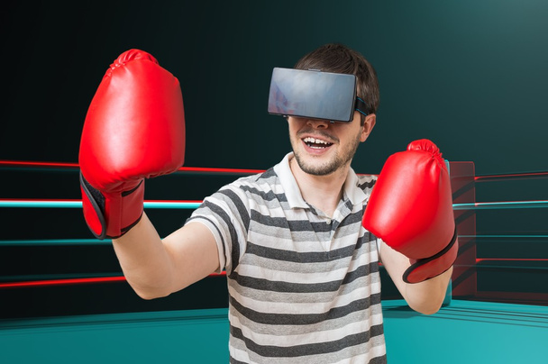 Young man is playing video game and is boxing in ring with 3D virtual reality headset. - 写真・画像