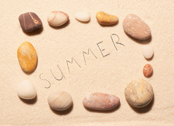 Frame of sea stones with summer lettering drawn on sand - Foto, Imagen