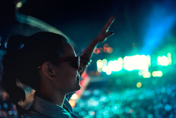 süslü kadın Festivali zevk, dans ve el hareketleri yapma. Müzik konserinde güneş gözlüklü kadın silüeti - Fotoğraf, Görsel