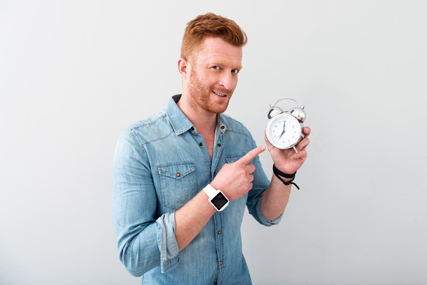 Pleasant delighted man holding alarm clock - Foto, imagen