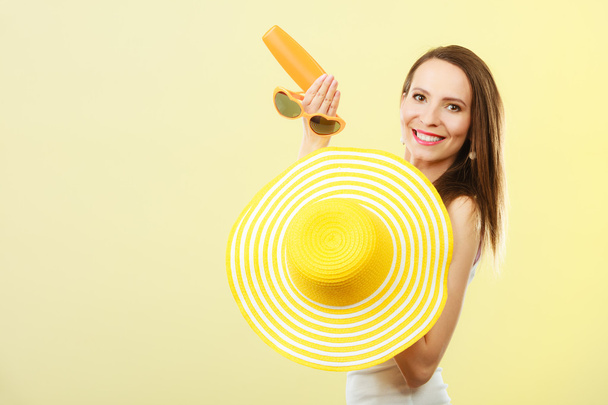 Woman in summer hat holds sunglasses sunscreen lotion - Photo, image