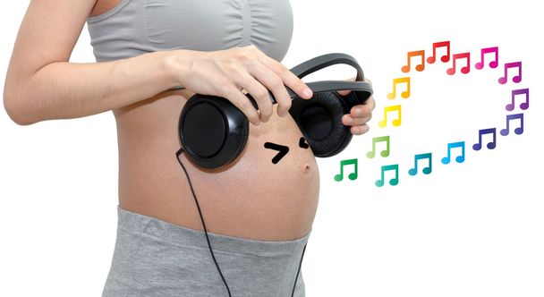 Zbliżenie ładny brzuch w ciąży kobiety z słuchawki. Na białym tle z miejsca kopiowania tle - Zdjęcie, obraz