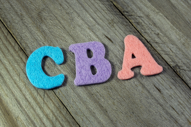 Acrónimo de CBA (Análisis coste-beneficio) sobre fondo de madera
 - Foto, imagen