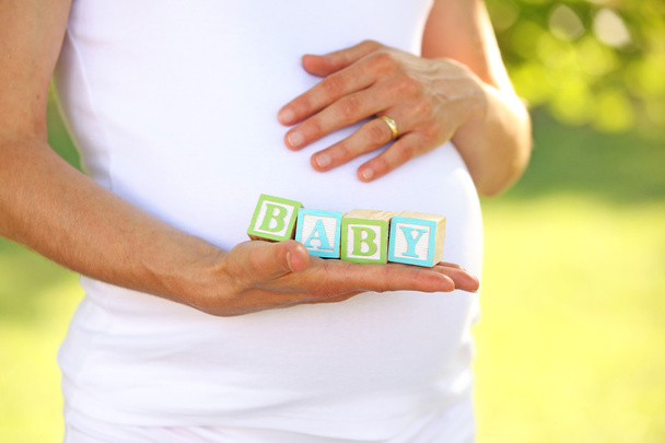 Беременная женщина держит слово ребенка
 - Фото, изображение