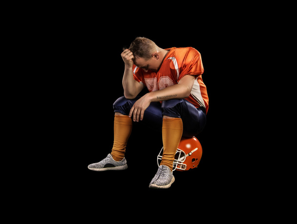 American football player sitting on helmet isolated - Fotoğraf, Görsel