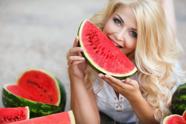 Beautiful young woman holding a slice of ripe watermelon - Фото, изображение