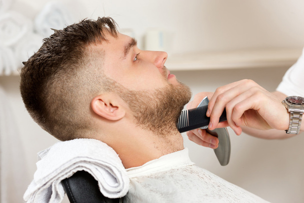 Молодой бородатый мужчина стрижется у парикмахера
 - Фото, изображение