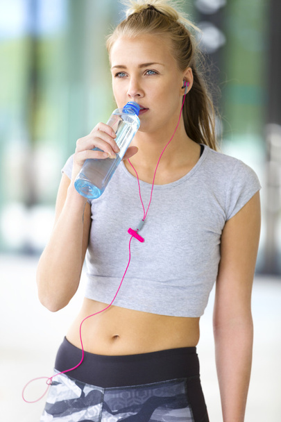 Nainen juo vettä harjoituksen jälkeen ulkona kaupungissa
 - Valokuva, kuva