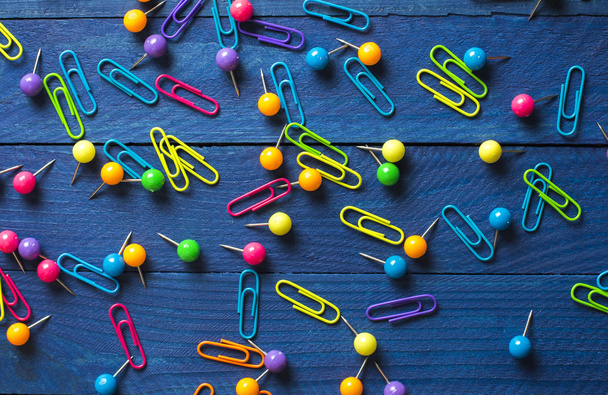 background of scattered colored round pins and paper clips on a table - Fotoğraf, Görsel