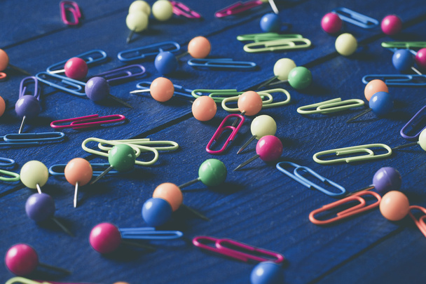 background of scattered colored round pins and paper clips on a table - Photo, Image