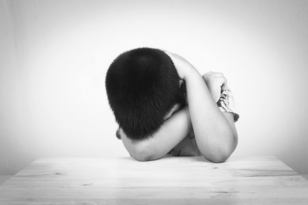 Garçon triste assis seul à la table en bois, noir et blanc
 - Photo, image