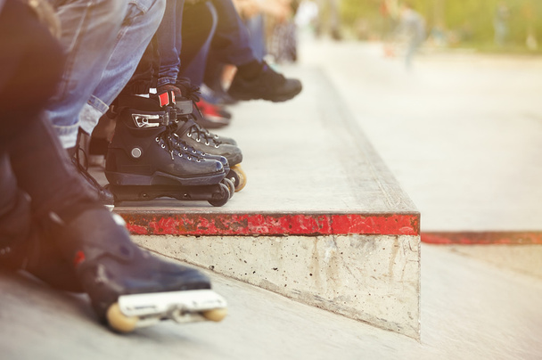 Aggressive inline rollerblader sitting in outdoor skate park - Фото, зображення