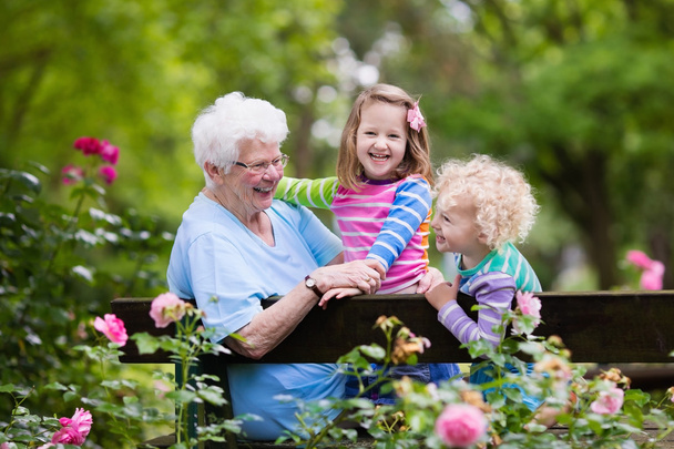 Avó e crianças sentadas no jardim de rosas
 - Foto, Imagem