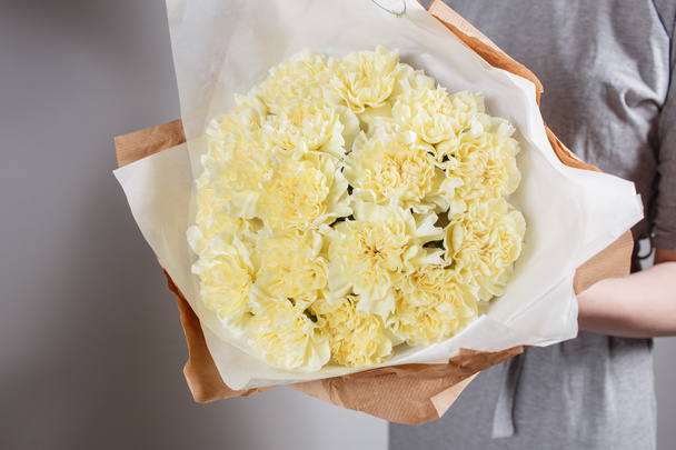 yumuşak sarı karanfil Çiçek çiçekçi elinde. Kraft kağıt - Fotoğraf, Görsel