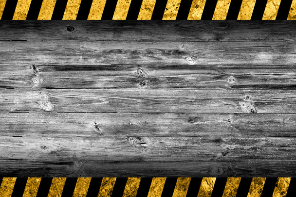 Grunge grauer Holzhintergrund mit schwarzen und gelben Warnstreifen - Foto, Bild