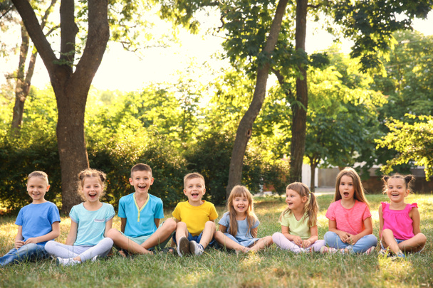 公園の芝生の上に座って幸せな子供 - 写真・画像