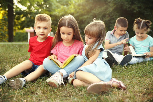 Group of happy kids reading books in park - Foto, afbeelding
