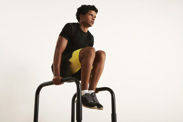 Strong young black athlete rising knees on parallel bars - Φωτογραφία, εικόνα