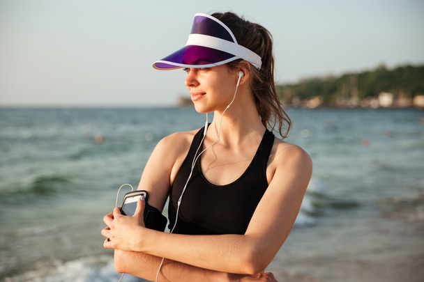 Fitness woman resting on beach listening to music with phone - Foto, afbeelding