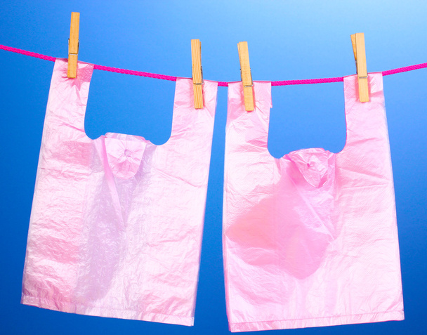 Cellophane bags hanging on rope on blue background - Foto, Imagen