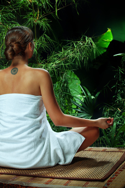 Uitzicht op de mooie jonge vrouw mediteren in een spa omgeving - Foto, afbeelding