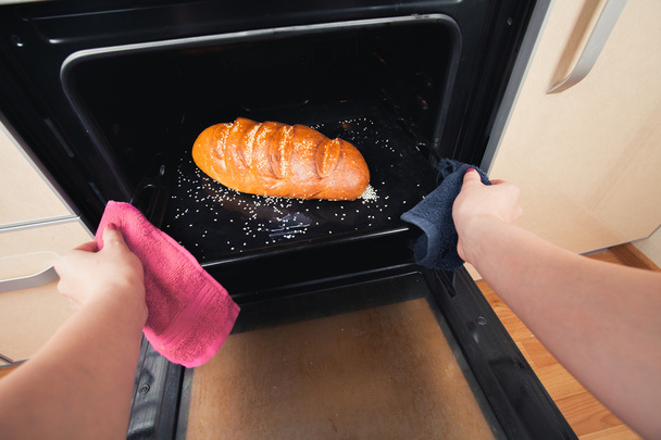 Руки девушки, чтобы достать хлеб из духовки
 - Фото, изображение