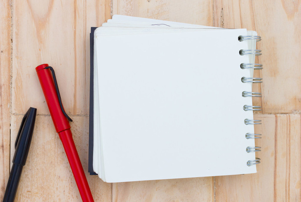 zbliżenie puste notebooka na brązowy drewniany stół, z czerwonym i czarnym piórem - Zdjęcie, obraz