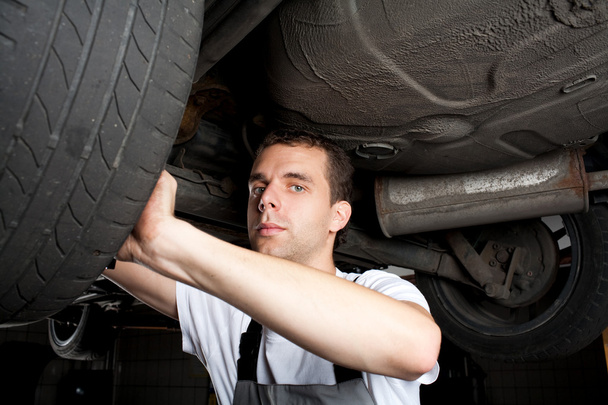 Closeup of mechanic working below car with wrench - Foto, Imagen