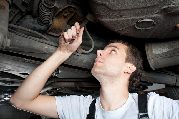 Closeup of mechanic working below car with wrench - Photo, Image
