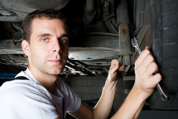 Closeup of mechanic working below car with wrench - Foto, Imagen