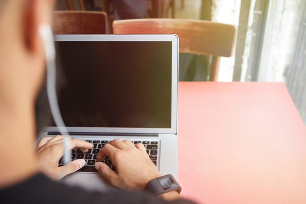 Молодой бородатый бизнесмен в черной футболке Рабочий ноутбук Городской Cafe.Man Сидящий деревянный стол наушники с помощью ноутбука пустой экран. Coworking процесс Бизнес Startup.Blurred фоне
 - Фото, изображение