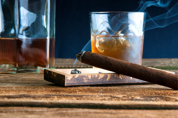 Sigaro e whisky con ghiaccio sul tavolo di legno
 - Foto, immagini