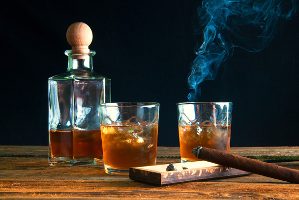 Cigarros y whisky con hielo sobre mesa de madera
 - Foto, imagen
