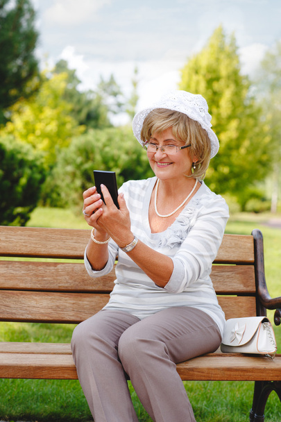 Belle femme mature utilisant un smartphone dans un parc
 . - Photo, image