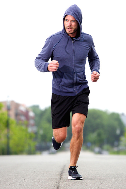 Confident middle age athlete running in street - Photo, Image