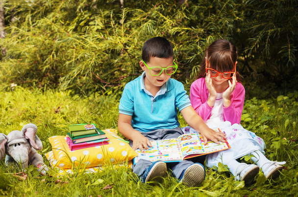 τα παιδιά, ένα αγόρι και ένα κορίτσι διαβάζοντας ένα βιβλίο με τα γυαλιά - Φωτογραφία, εικόνα