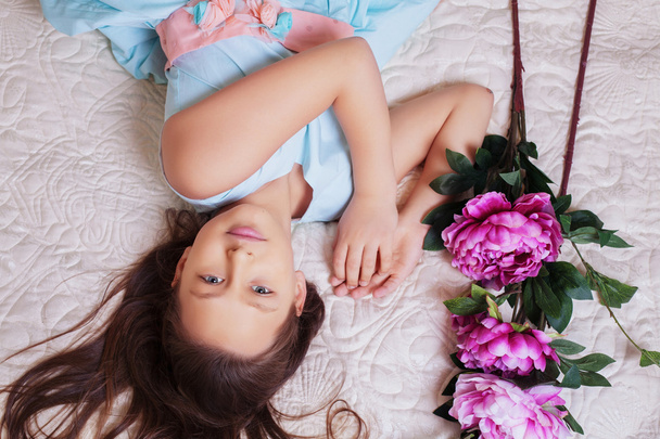 sweet little girl with long hair lying in flowers - Photo, Image