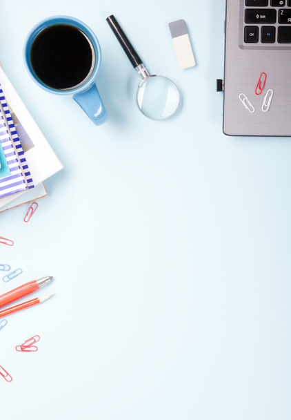 Escritorio de mesa de oficina con suministros, bloc de notas en blanco, taza, pluma, PC, papel arrugado, flor sobre fondo azul. Vista superior
 - Foto, Imagen