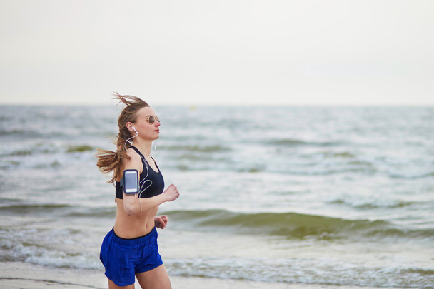 Молодая бегущая женщина бегает по пляжу
 - Фото, изображение