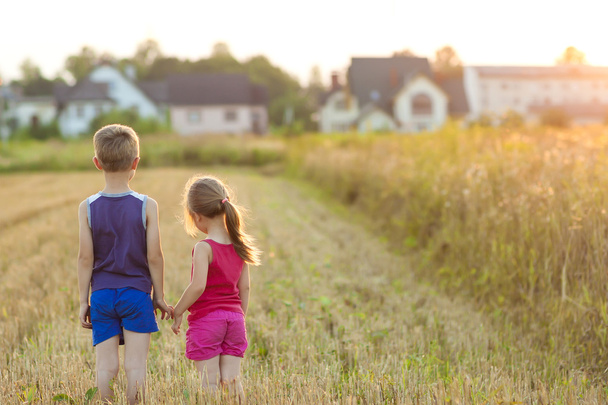 Девочка и мальчик стоят на поле с золотым солнечным светом
 - Фото, изображение