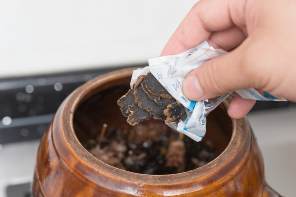 putting herbal to an enamel pot to decoct herbal medicine - Photo, Image